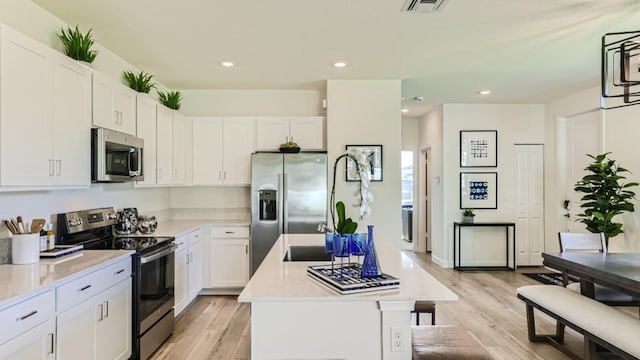 kitchen with a center island, light wood-type flooring, stainless steel appliances, and white cabinetry