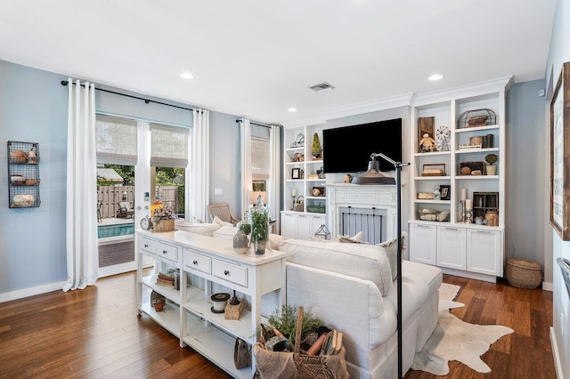 living room with a fireplace, dark wood-type flooring, and built in features