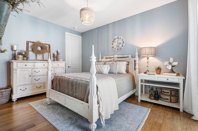 bedroom with dark wood-type flooring and an inviting chandelier