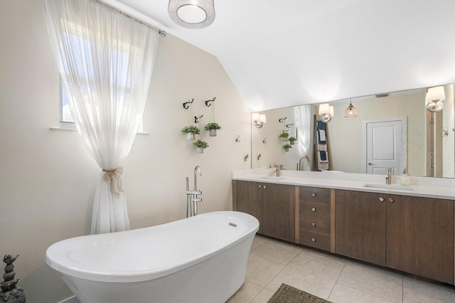 bathroom featuring tile patterned floors, a bathing tub, vanity, and vaulted ceiling