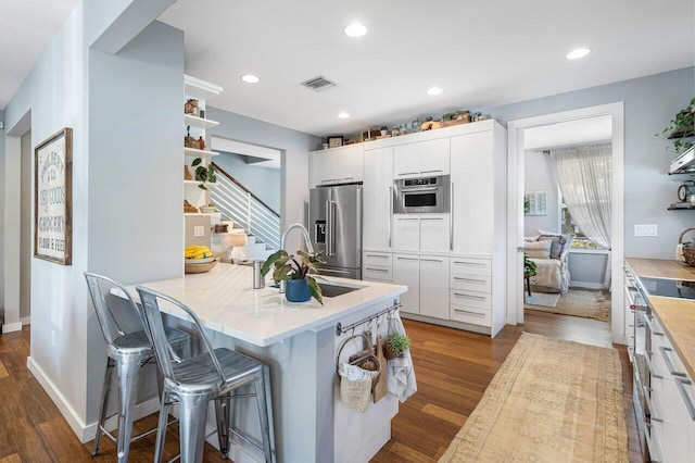 kitchen with sink, white cabinetry, stainless steel appliances, and a breakfast bar area