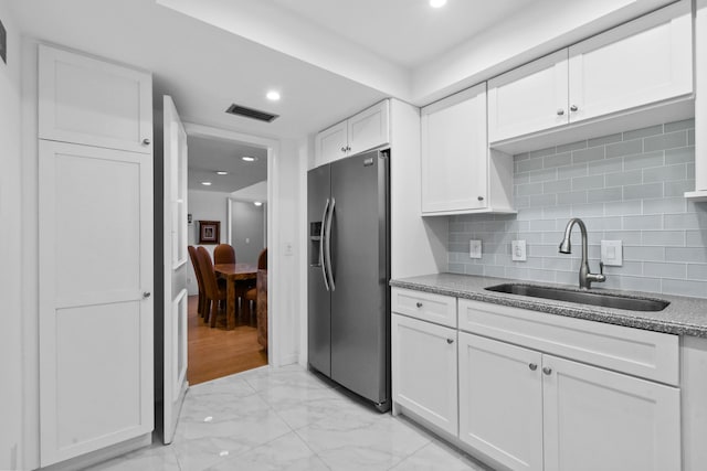 kitchen featuring backsplash, stainless steel fridge, sink, and white cabinets