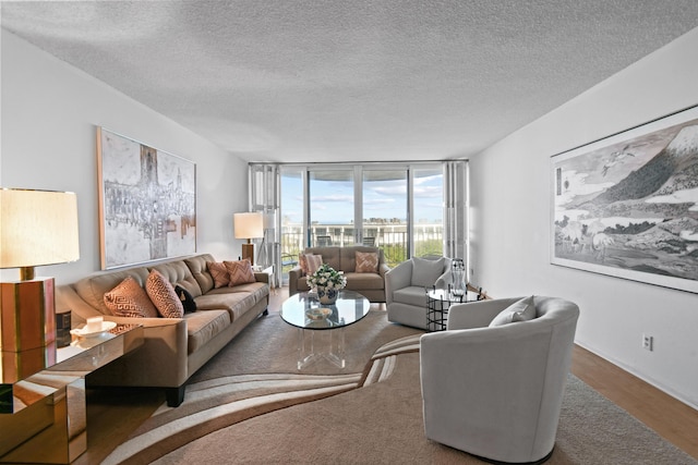 living room featuring wood-type flooring, a wall of windows, and a textured ceiling