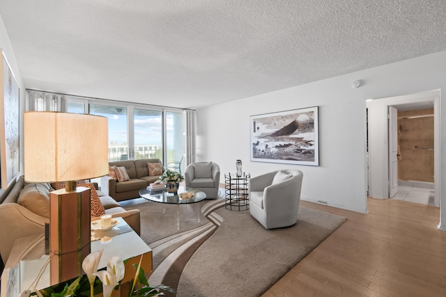 living room featuring a textured ceiling, light hardwood / wood-style flooring, and floor to ceiling windows