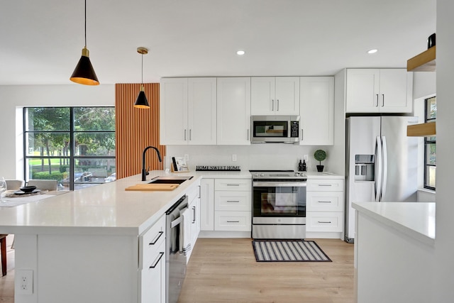 kitchen with white cabinetry, sink, kitchen peninsula, pendant lighting, and appliances with stainless steel finishes