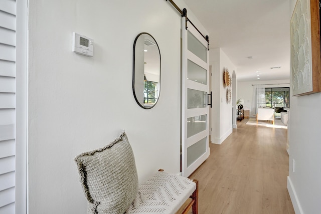 hallway with a barn door and light wood-type flooring