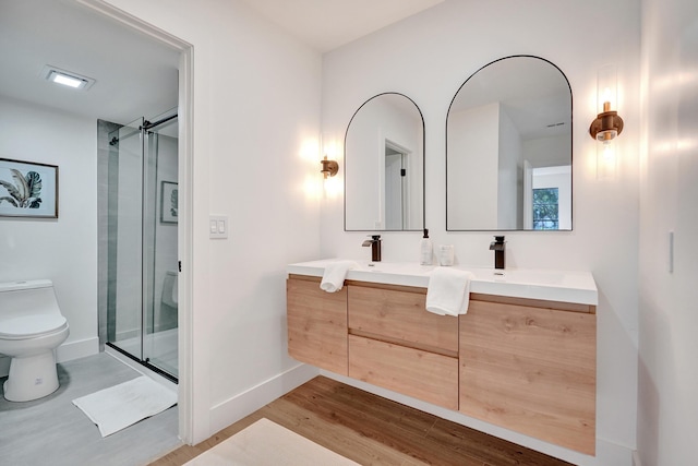 bathroom with hardwood / wood-style flooring, vanity, toilet, and a shower with door