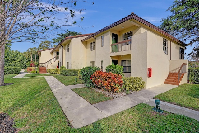 view of side of property with a yard and a balcony