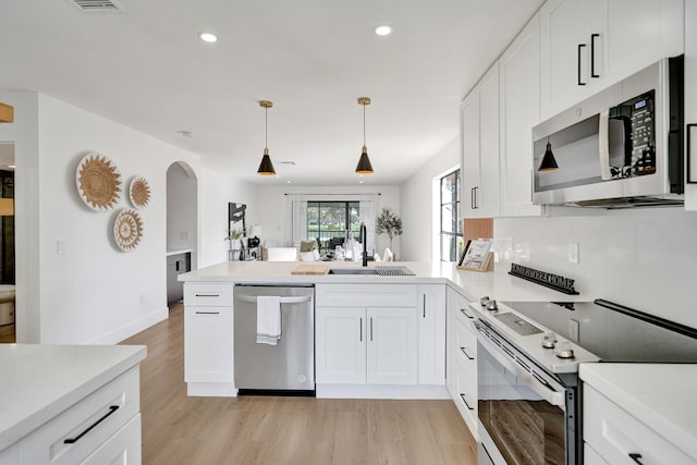 kitchen featuring white cabinetry, appliances with stainless steel finishes, sink, and decorative light fixtures