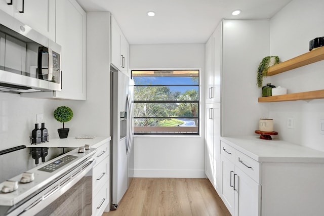 kitchen with stainless steel appliances, white cabinetry, and light wood-type flooring