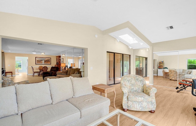 living room with ceiling fan, light wood-type flooring, and vaulted ceiling