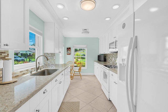 kitchen with white cabinets, light stone countertops, white appliances, and sink