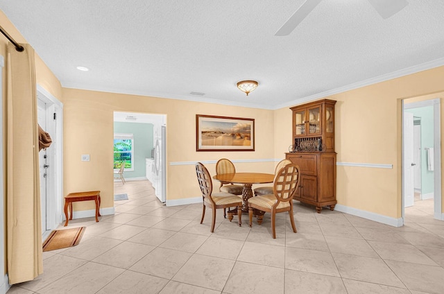 dining area with ornamental molding, a textured ceiling, and light tile patterned floors