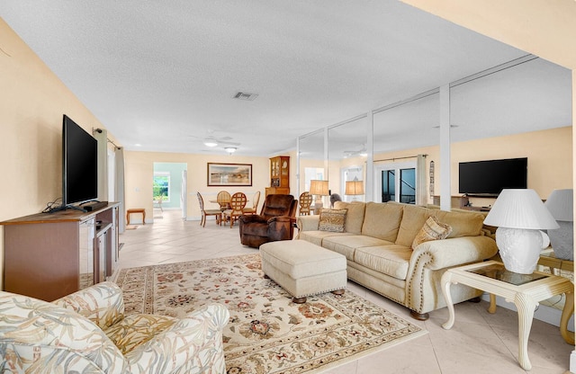 tiled living room with ceiling fan and a textured ceiling