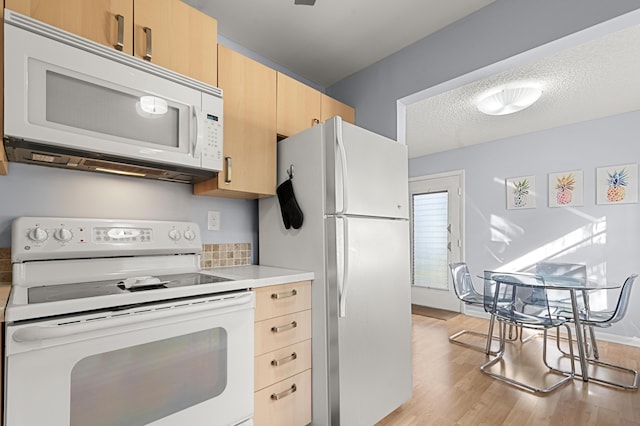 kitchen featuring white appliances, light wood-type flooring, a textured ceiling, and light brown cabinets