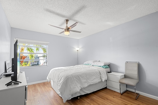 bedroom featuring ceiling fan, hardwood / wood-style flooring, and a textured ceiling