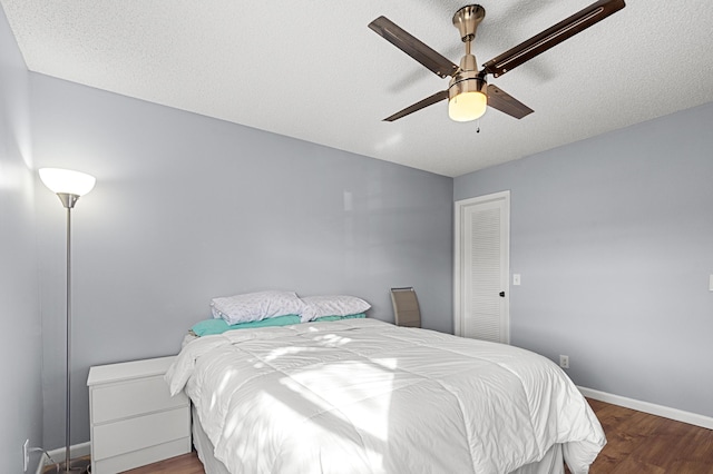 bedroom with dark wood-type flooring, a textured ceiling, and ceiling fan