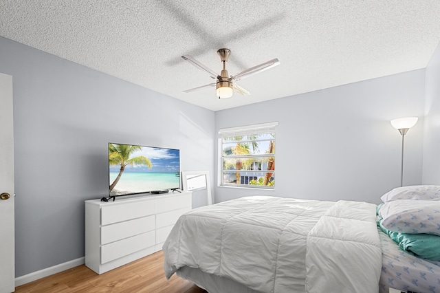 bedroom featuring ceiling fan, light hardwood / wood-style floors, and a textured ceiling