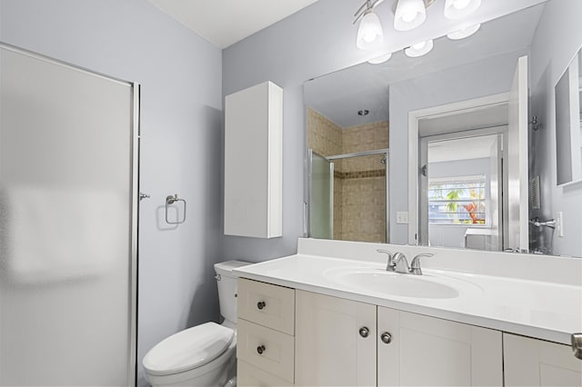 bathroom with vanity, a shower with door, and toilet