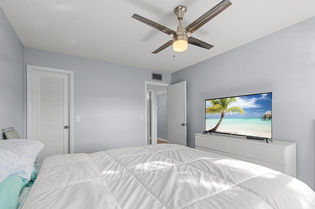 bedroom with ceiling fan and a textured ceiling