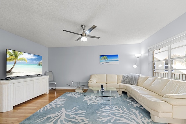 living room with hardwood / wood-style flooring, ceiling fan, and a textured ceiling