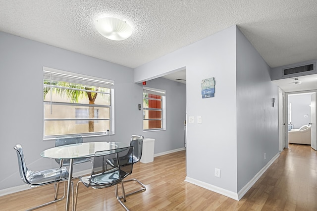 dining space with hardwood / wood-style floors and a textured ceiling