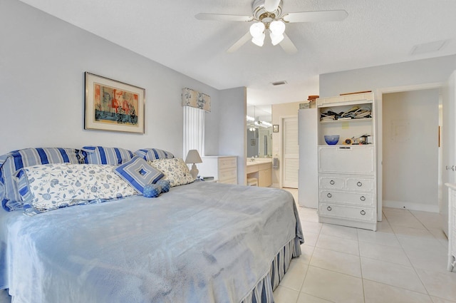 bedroom with ceiling fan, light tile patterned floors, ensuite bathroom, and a textured ceiling