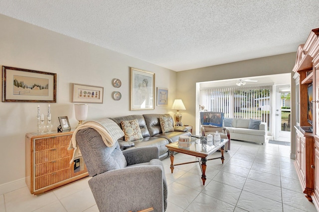 living room with ceiling fan, light tile patterned floors, and a textured ceiling