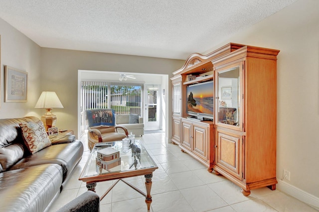 living room featuring ceiling fan, light tile patterned flooring, and a textured ceiling