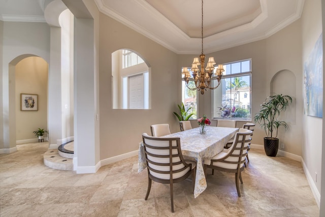 dining area with ornamental molding, a tray ceiling, and a notable chandelier