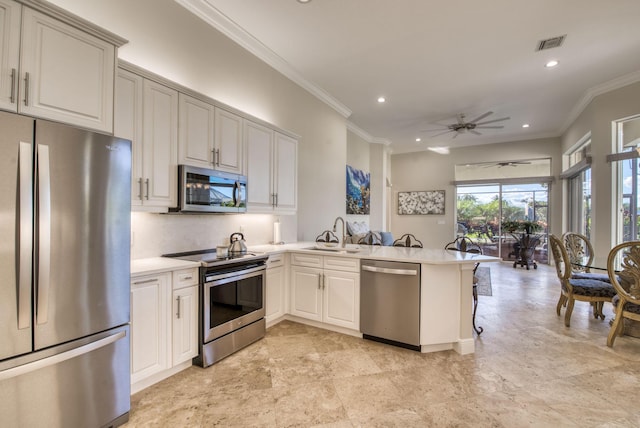 kitchen with kitchen peninsula, appliances with stainless steel finishes, ornamental molding, ceiling fan, and sink