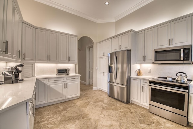 kitchen featuring gray cabinets, light stone counters, ornamental molding, and stainless steel appliances