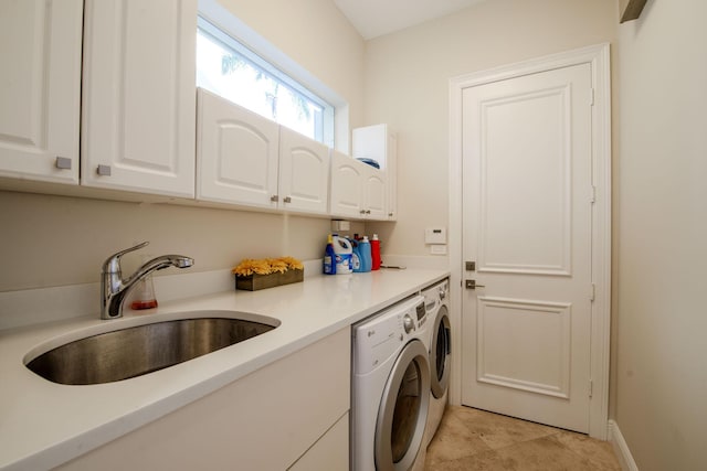 clothes washing area with washing machine and clothes dryer, sink, and cabinets