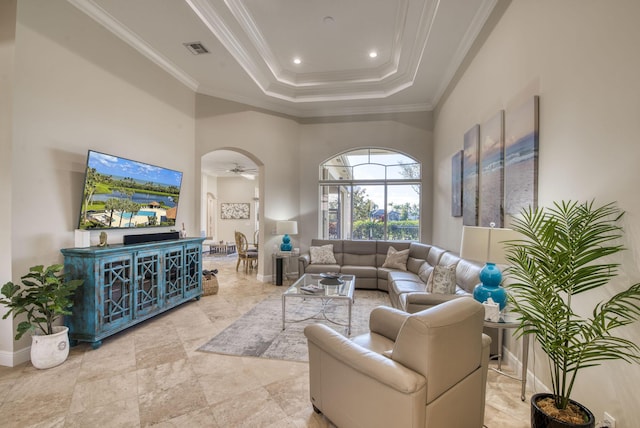 living room with a raised ceiling, ceiling fan, a high ceiling, and ornamental molding