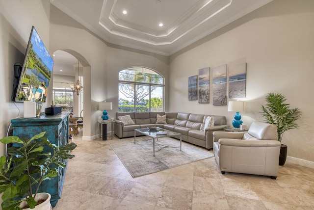 living room featuring a high ceiling, a raised ceiling, crown molding, and a notable chandelier