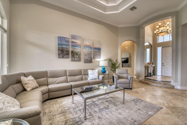 living room with a tray ceiling, crown molding, a towering ceiling, and a notable chandelier