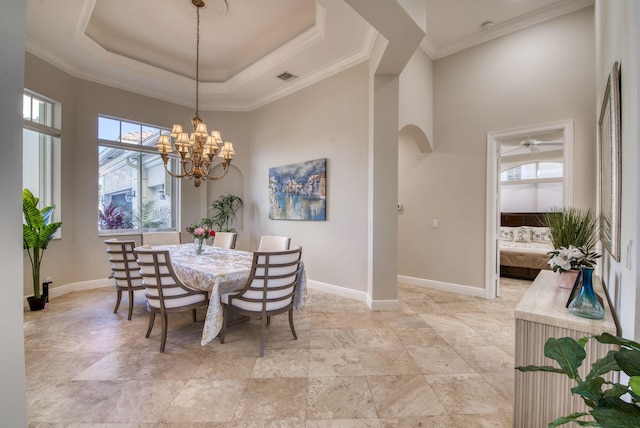 dining space with a tray ceiling, ornamental molding, and an inviting chandelier