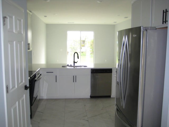 kitchen with kitchen peninsula, white cabinetry, sink, and appliances with stainless steel finishes