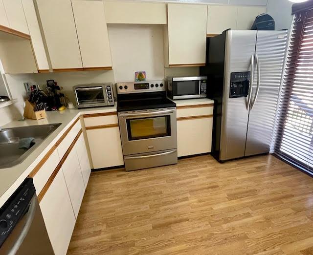 kitchen featuring white cabinets, appliances with stainless steel finishes, light hardwood / wood-style floors, and sink