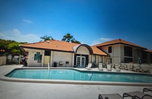 rear view of house featuring a community pool and a patio
