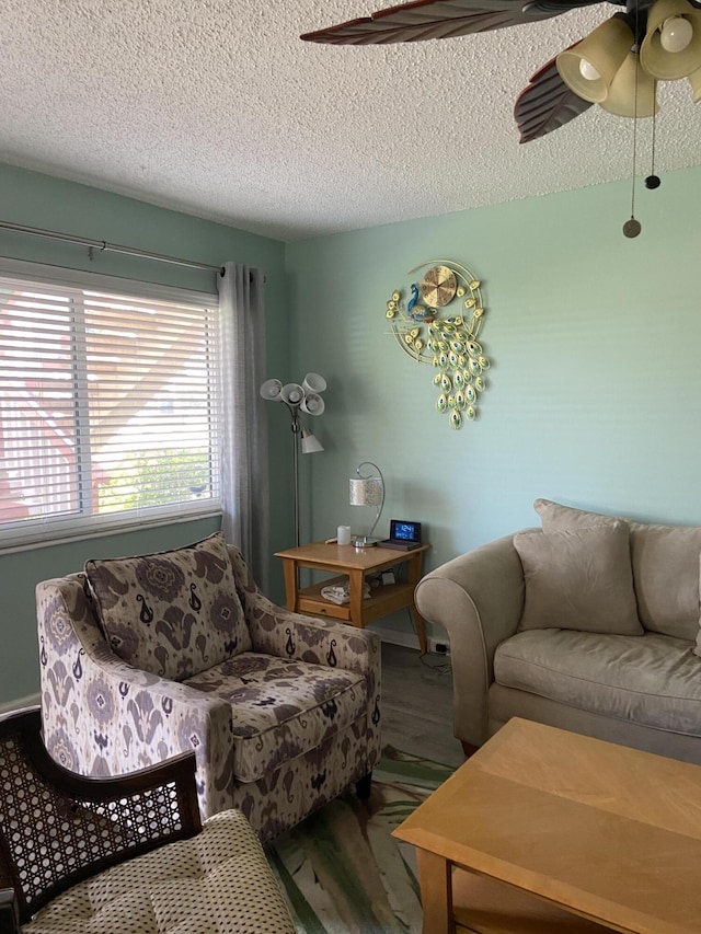 living room featuring ceiling fan, wood-type flooring, and a textured ceiling