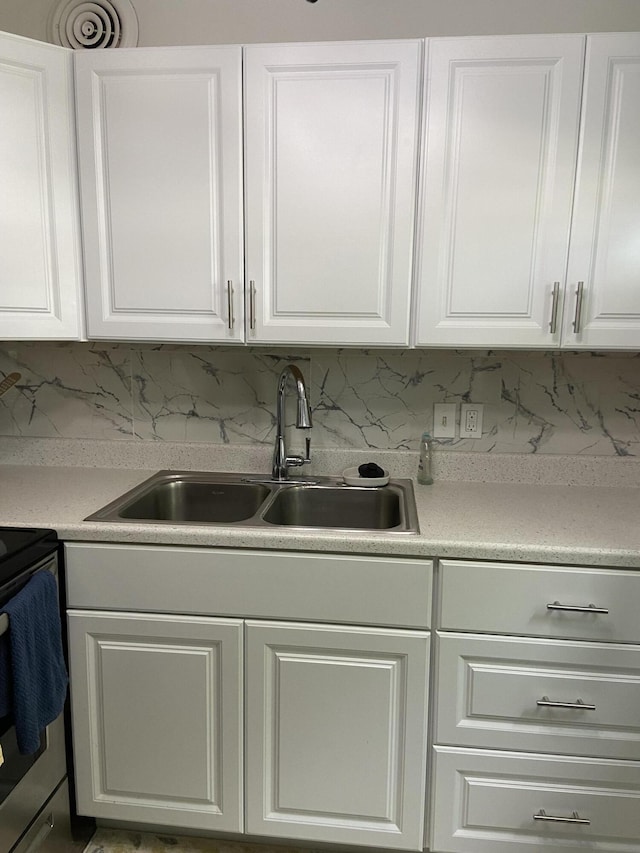 kitchen featuring white cabinets, sink, and tasteful backsplash