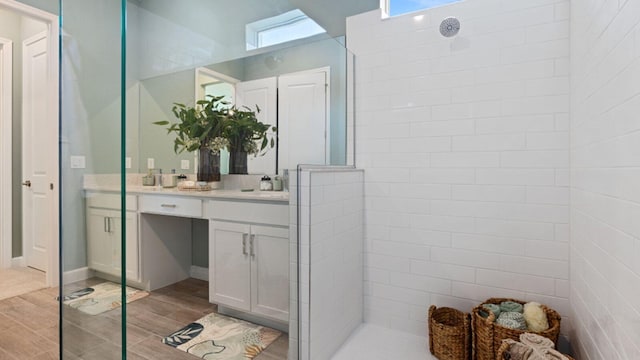 bathroom with hardwood / wood-style floors, plenty of natural light, a shower, and vanity