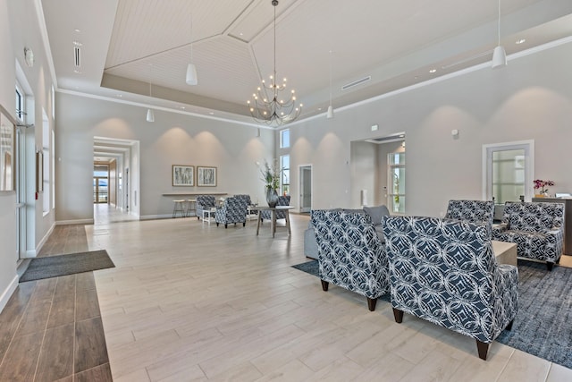 living room featuring a high ceiling, an inviting chandelier, light hardwood / wood-style flooring, and a raised ceiling