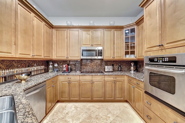 kitchen featuring dark stone countertops, decorative backsplash, sink, and appliances with stainless steel finishes