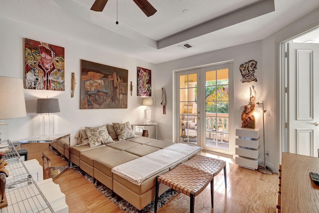 bedroom with french doors, light wood-type flooring, access to outside, a raised ceiling, and ceiling fan