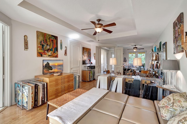 dining room featuring light wood-type flooring, a tray ceiling, and ceiling fan