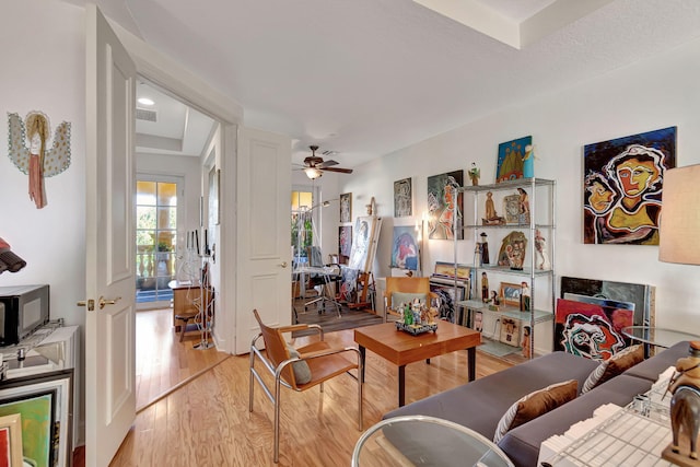 living room with ceiling fan, a fireplace, and light wood-type flooring