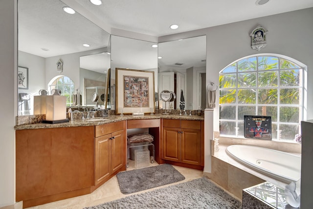 bathroom featuring vanity, a relaxing tiled tub, and tile patterned floors