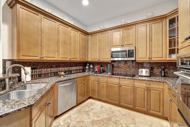 kitchen with dark stone counters, backsplash, sink, and stainless steel appliances